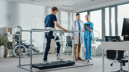 Wall Mural - Modern Hospital Physical Therapy: Patient with Injury Walks on Treadmill Wearing Advanced Robotic Exoskeleton. Physiotherapy Rehabilitation Scientists, Engineers, Doctors use Tablet Computer to Help