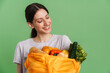© Drobot Dean - Young brunette woman smiling while holding textile bag with vegetable