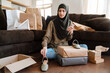 © Drobot Dean - Muslim woman using cellphone while sitting on floor with shopping bags