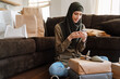 © Drobot Dean - Muslim woman using cellphone while sitting on floor with shopping bags