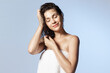 © deniskomarov - Happy young girl wrapped in towel with wet hairs, naked shoulders after bathroom. Ad for natural hair shampoo. Smiling young woman enjoying pure fresh hair. Beauty routine, hygiene, haircare concept