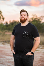 Portrait Of A Young Aussie Man With Beard, Outside At Dusk Wearing Black T-shirt