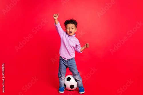 Full length body size view of attractive carefree preteen guy playing football isolated over bright red color background