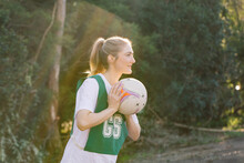 Side View Shot Of A Young Woman In Sports Wear Holding A Net Ball With Two Hands On A Sunny Day