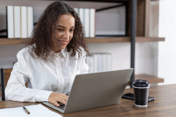 Young business woman working  and typing with laptop computer in the office. Smiling woman working with laptop computer