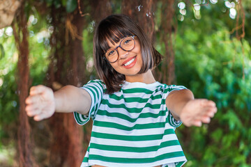 Wall Mural - Young brunette woman at outdoors in a park presenting and inviting to come with hand