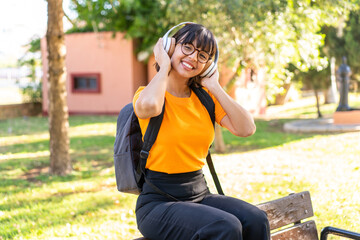 Wall Mural - Young student woman in a park listening music