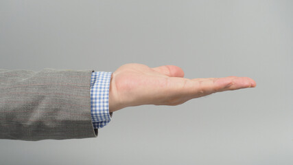 Wall Mural - Empty Hand gesture in grey suit on grey background. Businessman topic