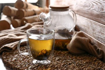 Poster - Wicker mat with freshly brewed tea near wooden wall in room. Cozy home atmosphere