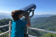 © Anna - Boy is looking into big iron binocular on mountain viewpoint.  Travelling in beautiful places.