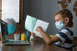 © Anna - Schoolboy during distant online lesson. He is showing homework in notebook to his teacher via laptop screen. Education during pandemic
