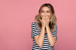 © Yury - Surprised young woman excited cover open mouth and look side happy laughing over pink studio wall. Young blonde female amazed with happiness in positive shock cheering to good amazing news isolated