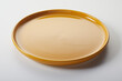 Round ceramic plate with shiny orange enamel on white background