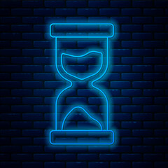 Poster - Glowing neon line Old hourglass with flowing sand icon isolated on brick wall background. Sand clock sign. Business and time management concept. Vector