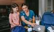 © David Pereiras - Mother preparing emergency backpack with her daughter in the kitchen