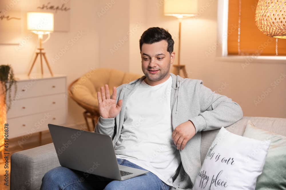 Young man video chatting at home late in evening