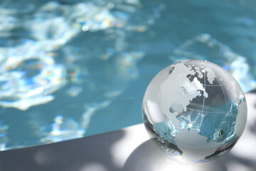 ガラスの地球儀と輝く水面　水の惑星　SDGsなどイメージ　glass globe and shining water surface