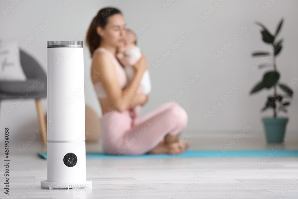 Modern humidifier in room with mother and her baby