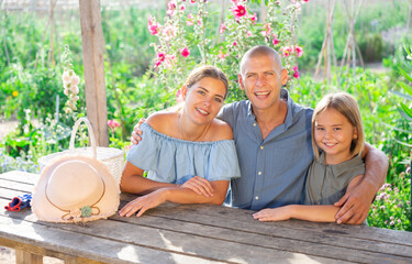 Wall Mural - Portrait of happy family at table in the courtyard of country house