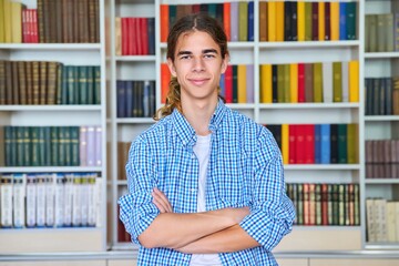 Wall Mural - Single portrait of smiling confident male student teenager looking at camera in library