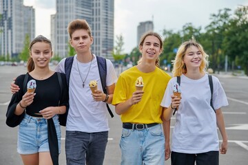 Wall Mural - Group portrait of happy teenagers walking together with ice cream