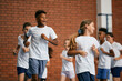 © Drazen - Multi-ethnic group of school children run during physical education class at school gym.