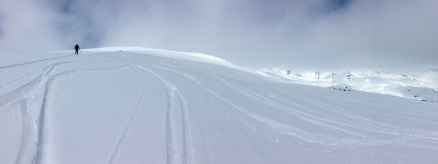 Wall Mural - panoramic view on mountain covered with snow and ski tracks of a touring skier climbing mountain