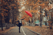 Girl With A Red Umbrella, Flying On An Umbrella, Jumping And Having Fun In A Yellow Autumn Landscape