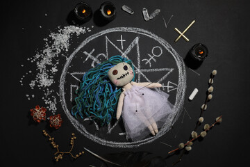 Wall Mural - Female voodoo doll with pins surrounded by ceremonial items on black background, flat lay