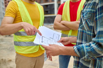 Poster - Three adult men discussing a new house plan outdoors