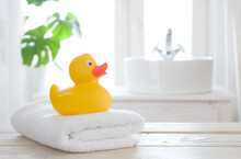 Towel And Bath Duck On Table On Blurred Bathroom Background