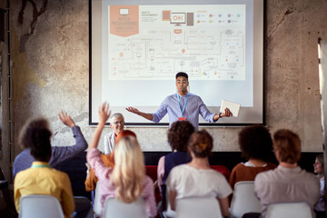 young afro american male giving presentation to a group of employees with his elderly caucasian fema