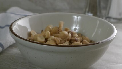 Wall Mural - Salted peanuts falling into a bowl in slow motion