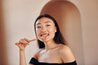 © standret - Holds toothbrush. Young serious asian woman standing indoors