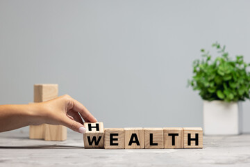 Female hand fliping wooden cubes with word wealth to health. Copyspace for ad, offer.