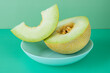 Half yellow melon with seeds and a cut and clean portion of seeds on a blue deep plate