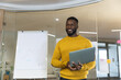 © Wavebreak Media - Smiling african american male business creative holding laptop, making presentation