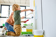 © Roman - Nice Mother and son painting house wall and having fun, Repair In Apartment Flat. Caucasian family, child boy and pleasant mom enjoy painting the wall together, teach and learn. side view