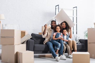 african american couple sitting under paper roof on sofa