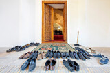 Fototapeta Miasta - Shoes taken off to get in the mosque with people praying in the background, Samarkand, Uzbekistan