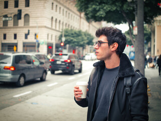 Attractive young man in modern city center drinking coffee