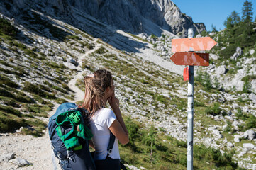 Young female hiker with a backpack contemplating standing by a signpost