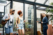 © Drazen - Happy receptionist greets tourist couple at hotel entrance.
