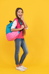 Wall Mural - surprised teen school girl with backpack go to study on yellow background, education