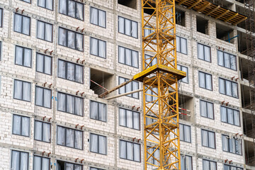 View of frame part of metallic crane machinery attachment at windows of new residential building construction site