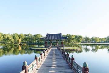 Wall Mural - Bridge that goes over a lake up to a traditional building surrounded by a forest in South Korea