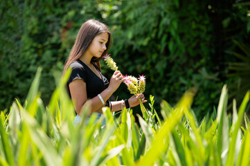 A charming girl with a pleasant smile and long dark hair. A beautiful girl enjoying the summer and clear weather on the meadow.