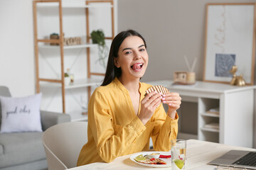 Sticker - Beautiful young woman eating tasty quesadilla at home