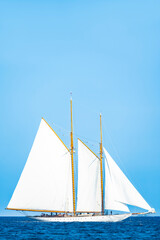 Wall Mural - Stunning view of a wooden sailboat with white sails sailing on a blue water during a sunny day. Isola di Spargi, Maddalena Archipelago, Costa Smeralda, Sardinia, Italy.