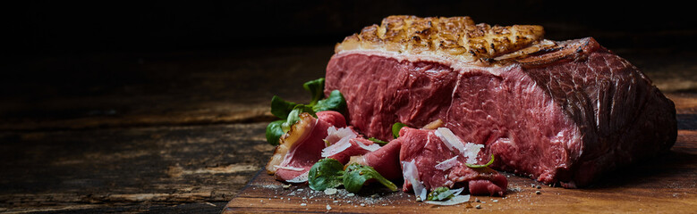 Wall Mural - Tasty grilled beef fillet with flake salt and green herbs placed on a wooden table